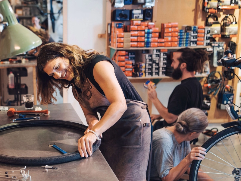 Fahrradmechanikerin arbeitet im Team mit guter Laune Fahrradmechanikerin arbeitet im Team mit guter Laune