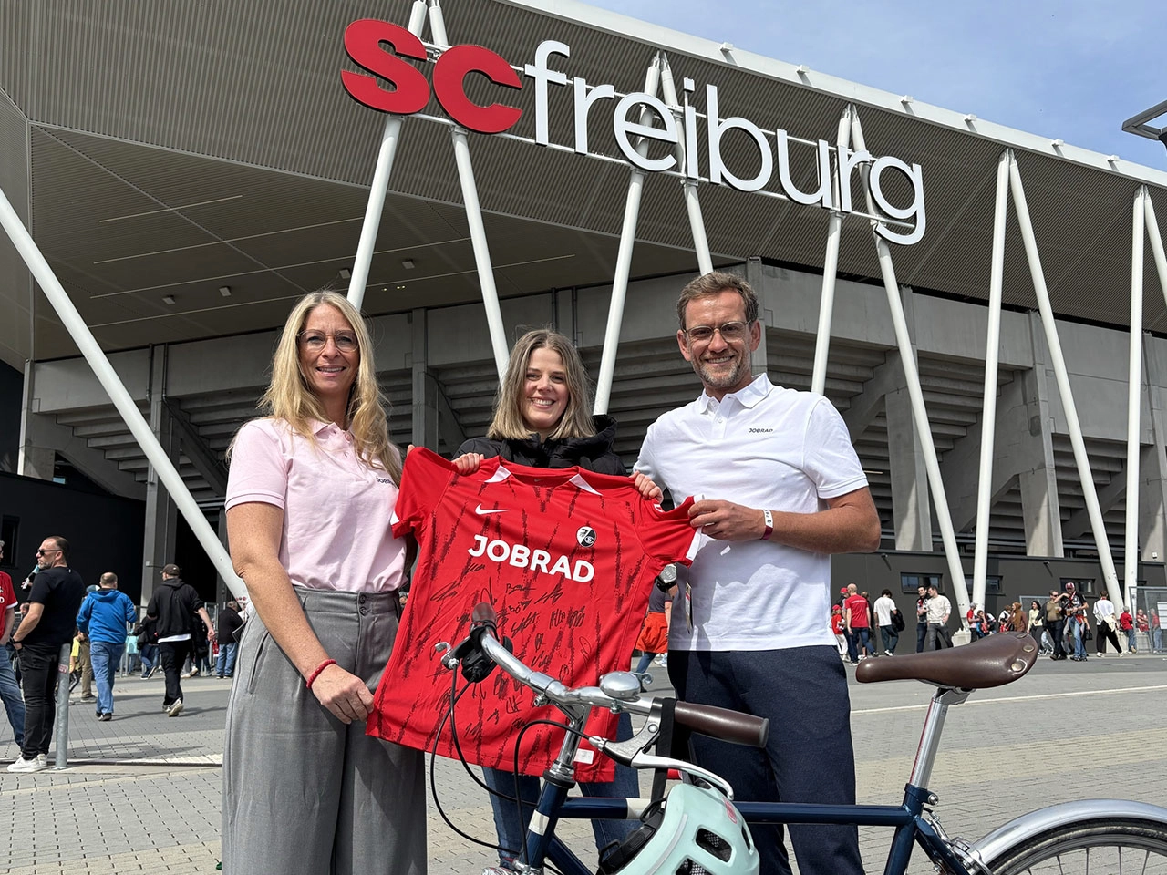 Sandra und Ulrich Prediger überreichen dem 200.000 Fahrrad-Fan ein SC-Trikot vor dem Europa-Park Stadion